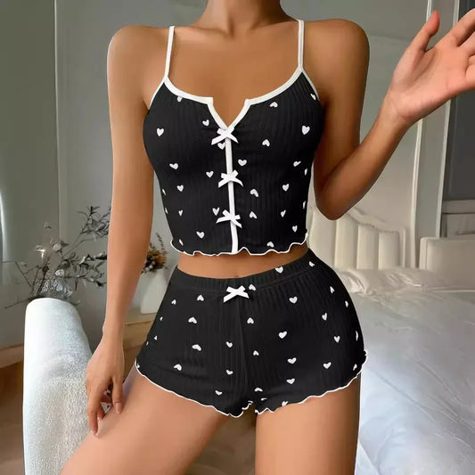 Black and white heart-patterned pajama set worn by a woman in a bedroom setting.