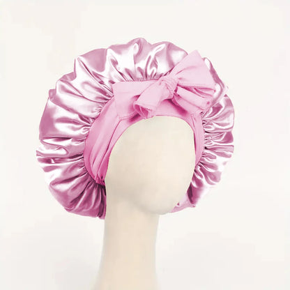 Pink satin bonnet with a bow on a mannequin head against a light pink background
